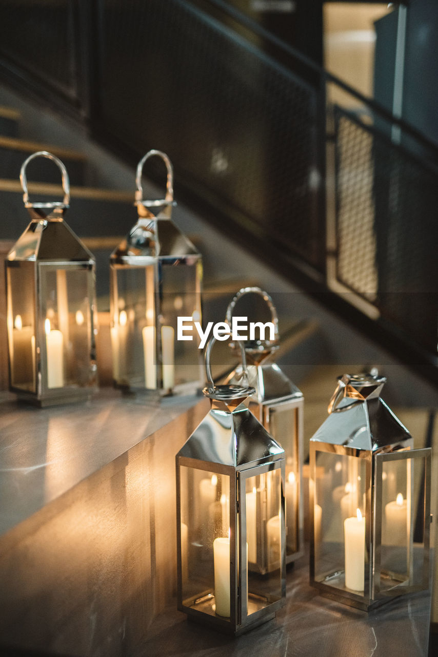 CLOSE-UP OF ILLUMINATED CANDLES ON TABLE AGAINST WALL