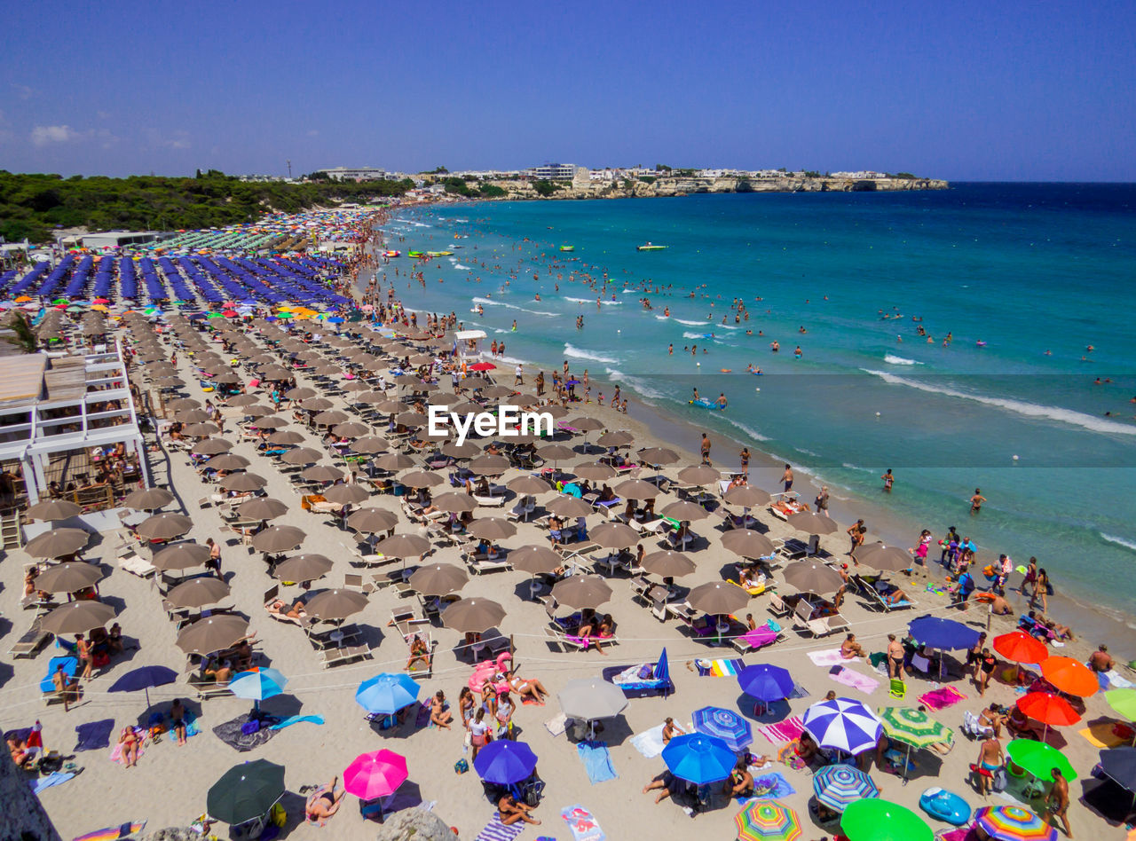 HIGH ANGLE VIEW OF PEOPLE ON BEACH AGAINST SKY