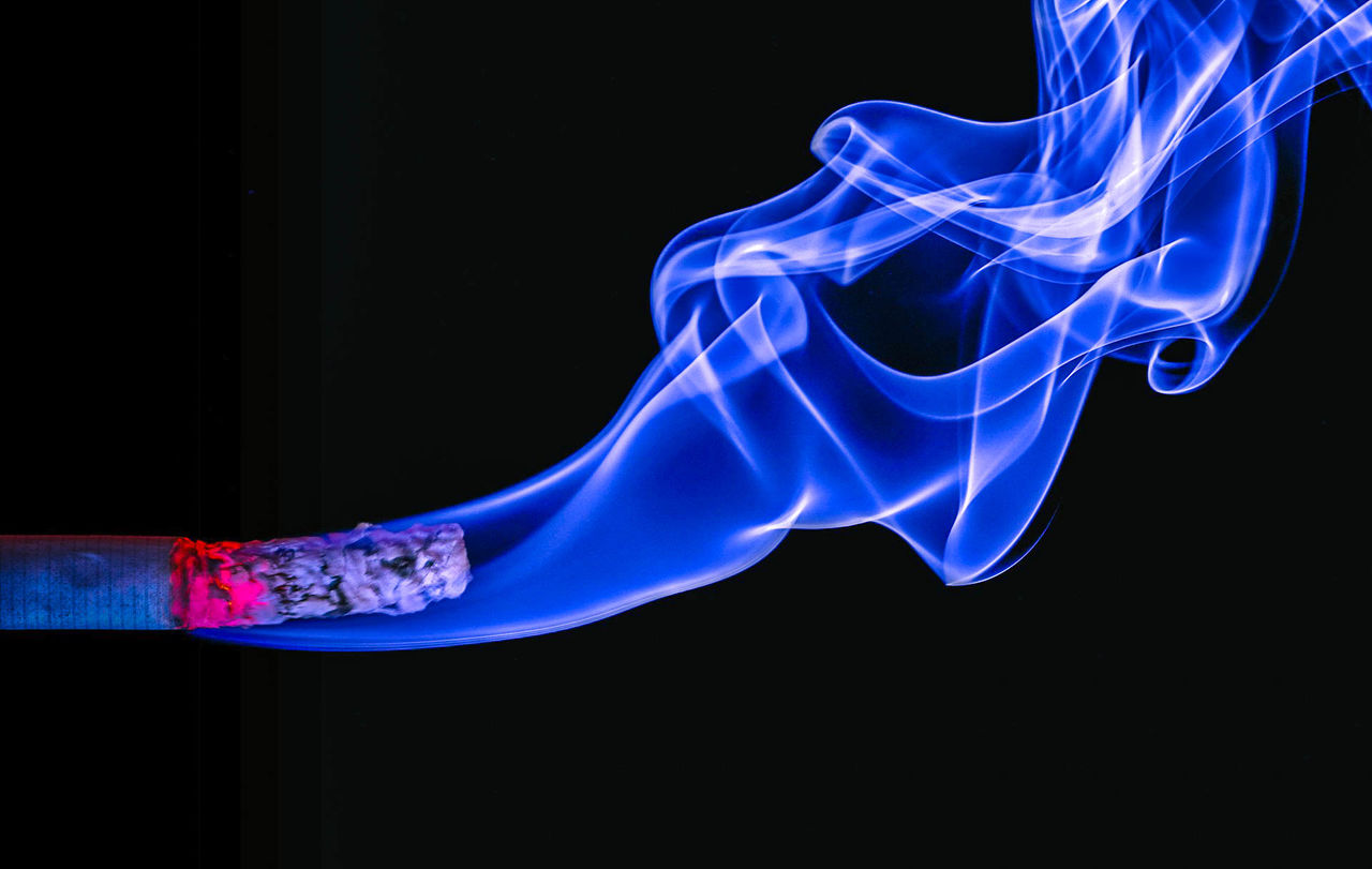 Close-up of burning cigarette against black background