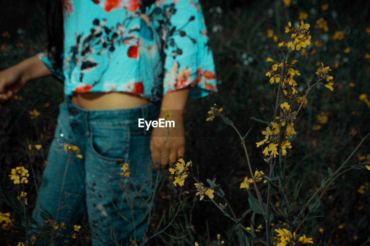 Midsection of woman standing by flowering plants