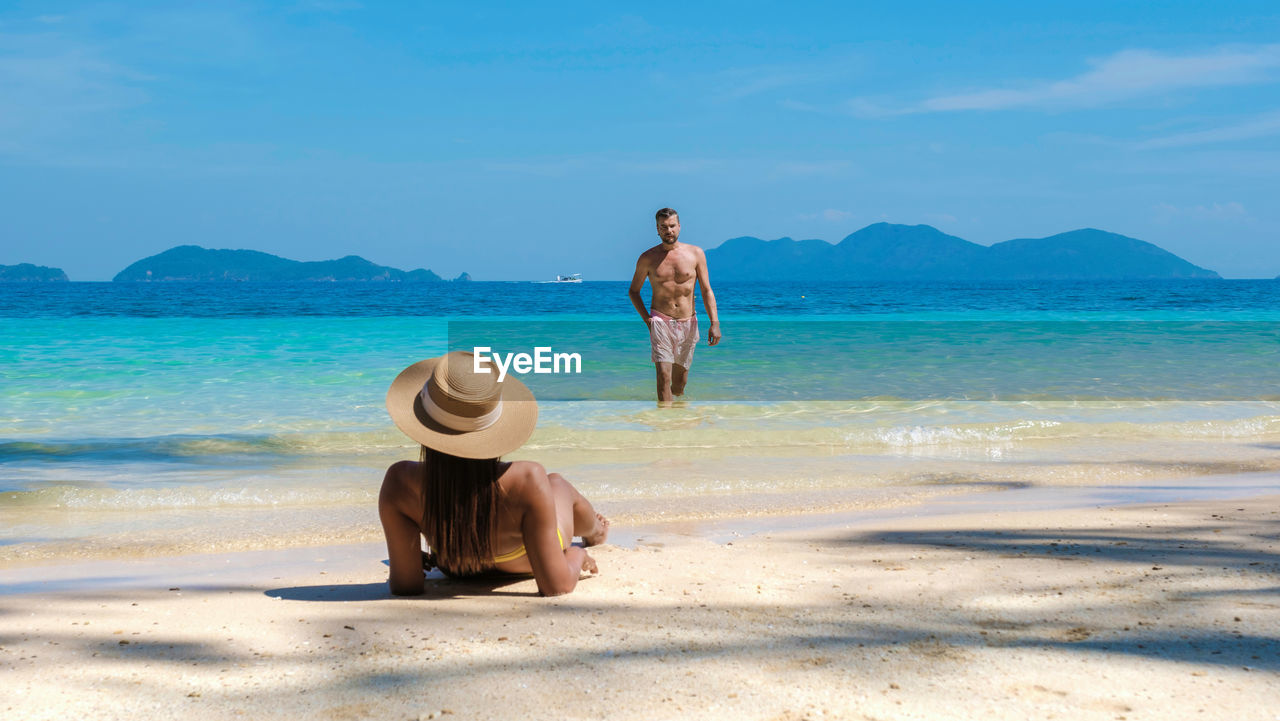 rear view of woman standing on beach against sky