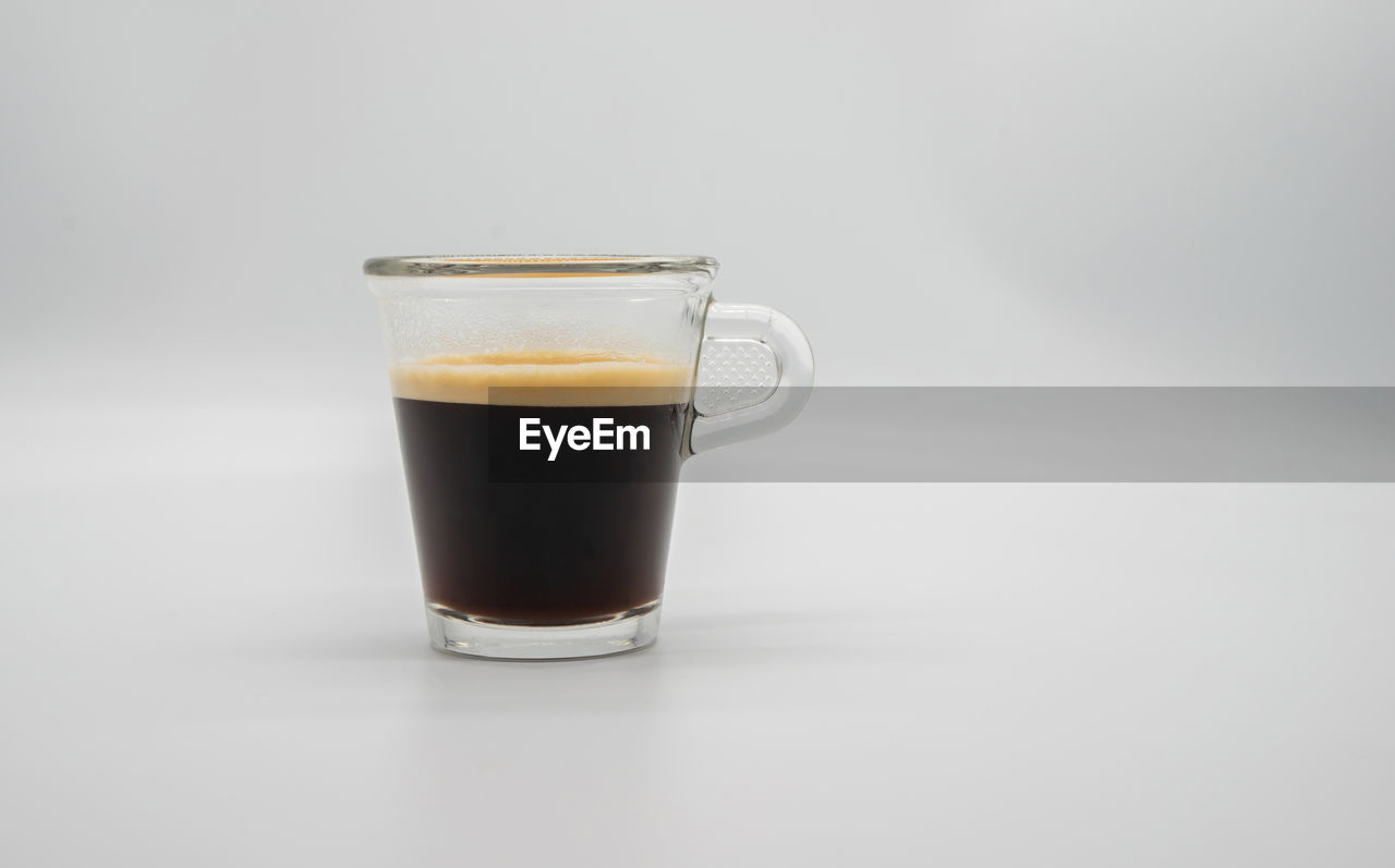 CLOSE-UP OF COFFEE IN GLASS AGAINST WHITE BACKGROUND