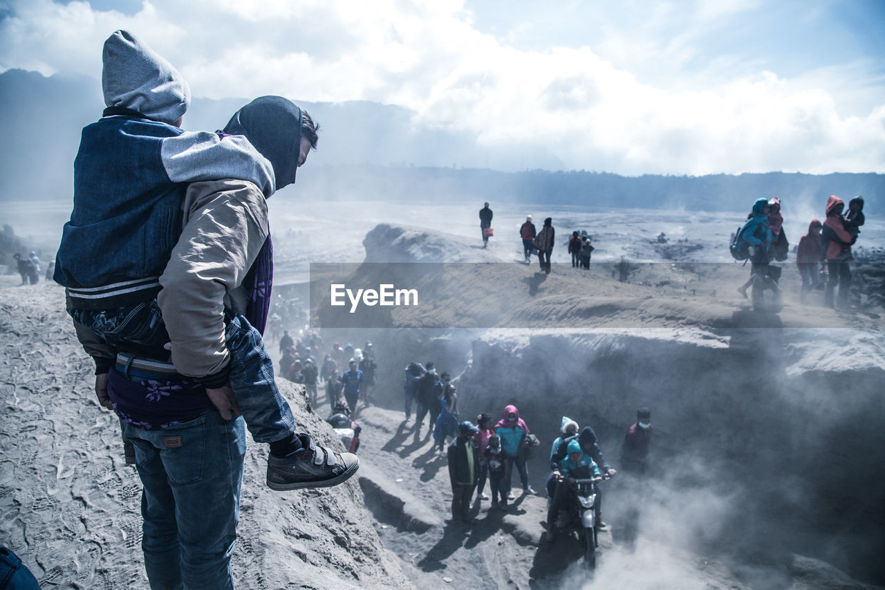 People on mountain against sky during foggy weather
