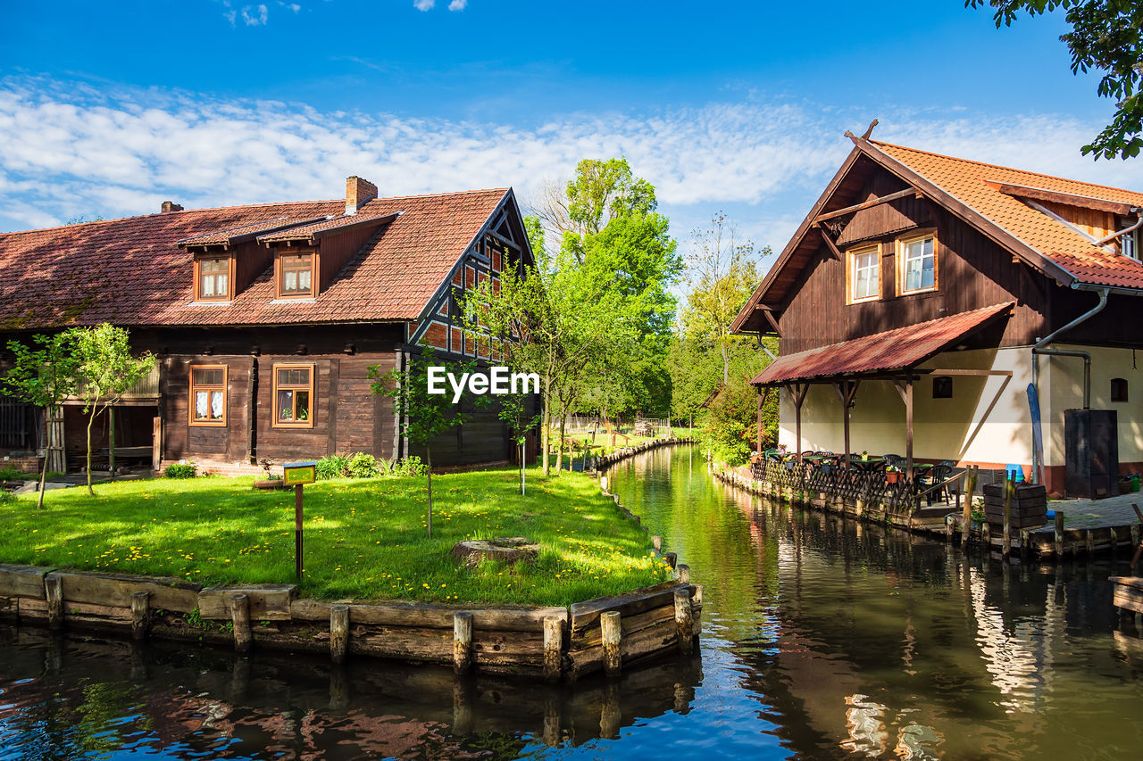 Houses by lake and buildings against sky