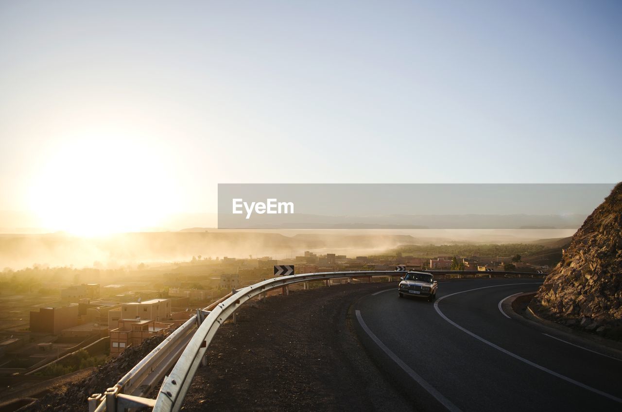 Road amidst landscape against clear sky during sunset