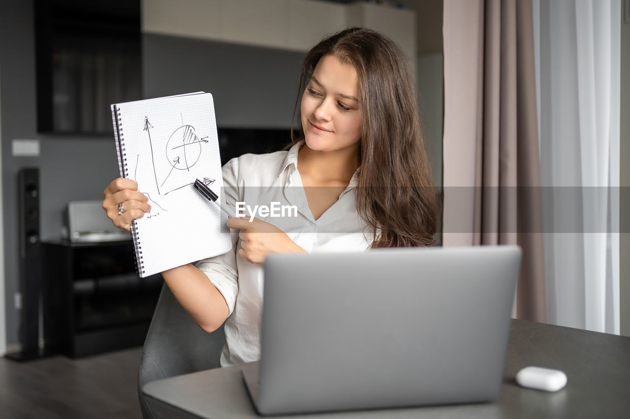 midsection of woman using digital tablet while sitting on table