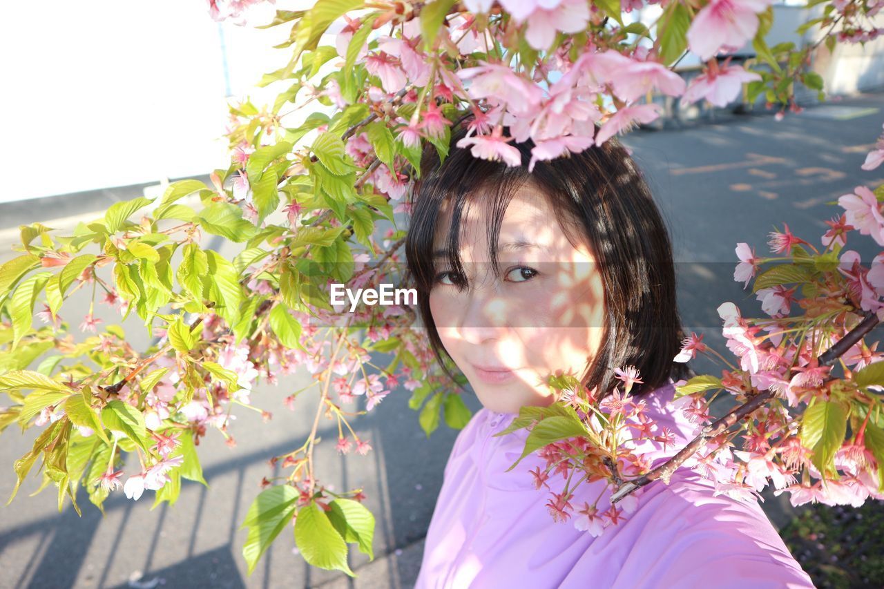 Portrait of woman with pink flowering plant