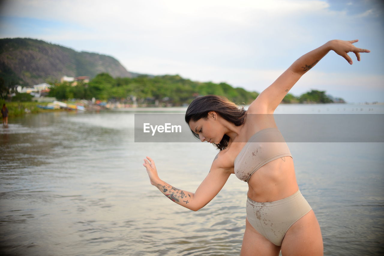 Young woman dancing against lake