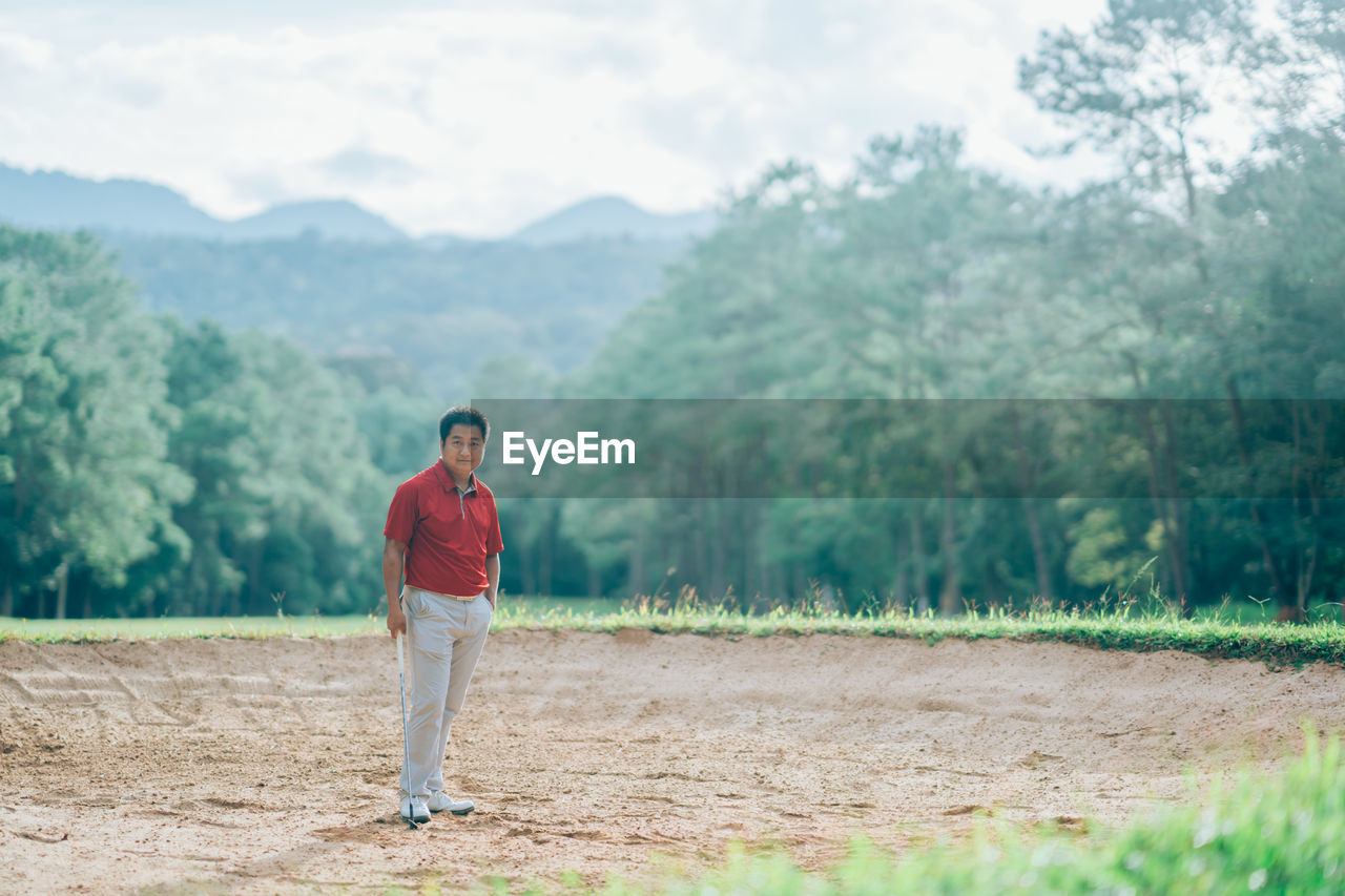 FULL LENGTH PORTRAIT OF MAN STANDING ON FIELD