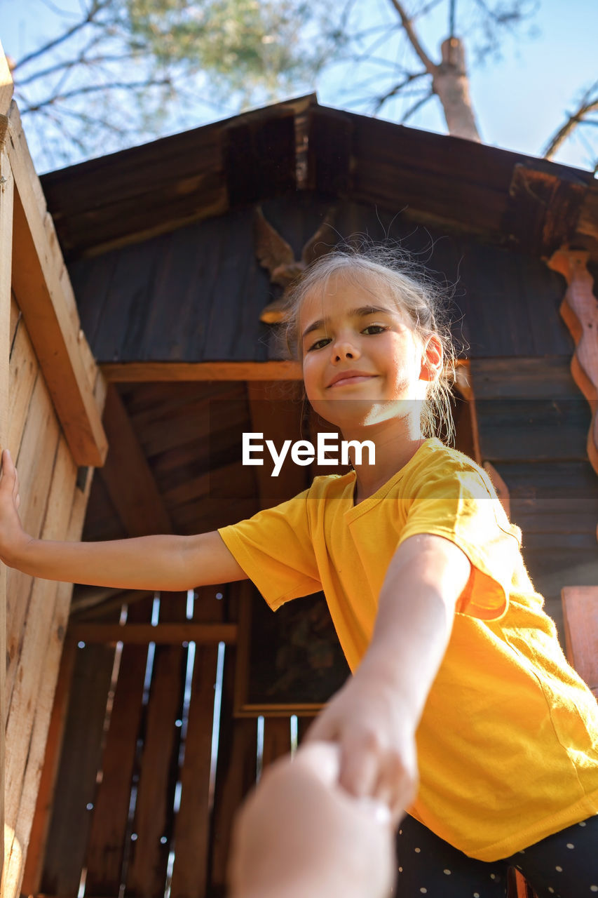 Girl plays in creative handmade treehouse in backyard, summer activity, happy childhood, cottagecore