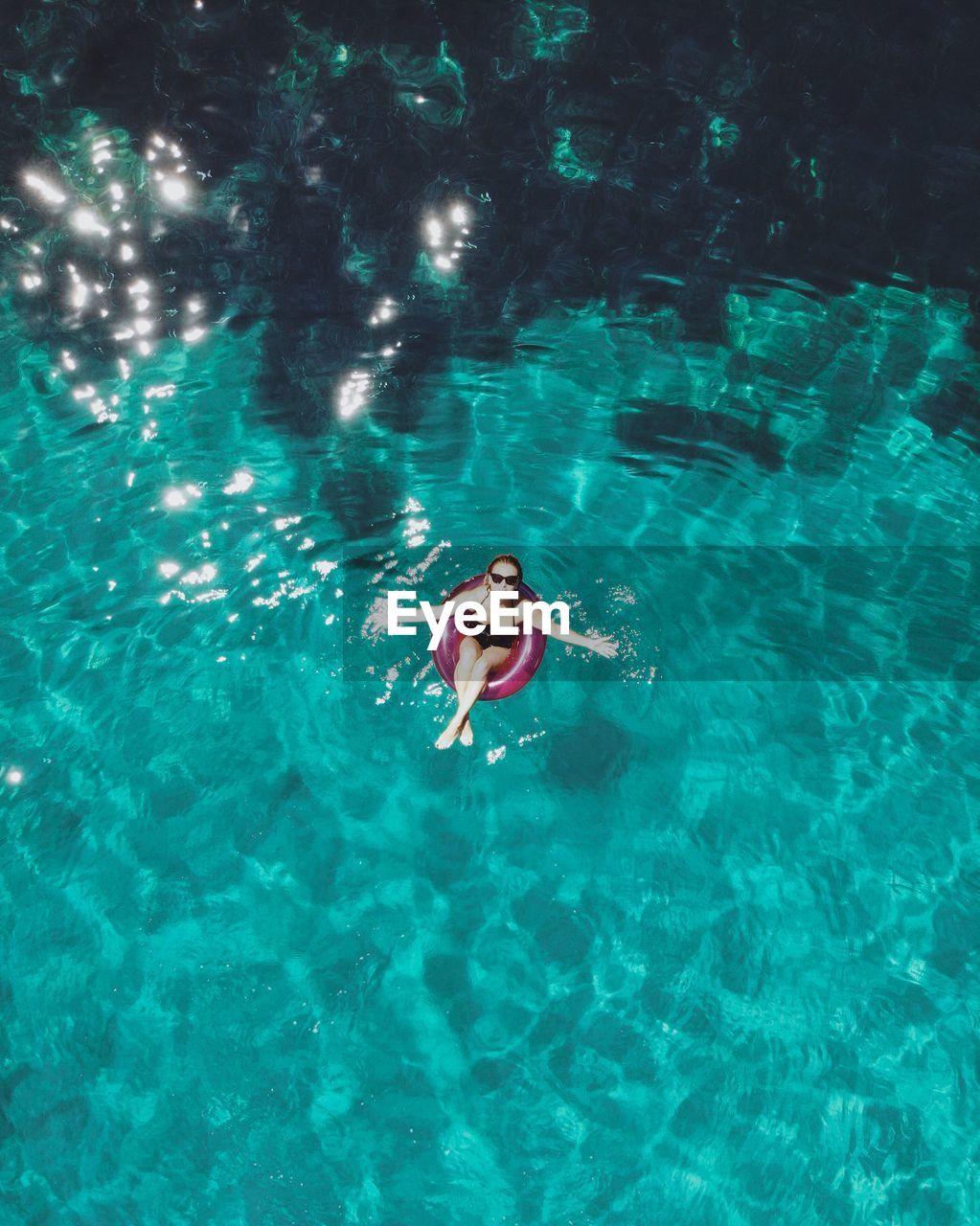 HIGH ANGLE VIEW OF WOMAN SWIMMING IN SEA