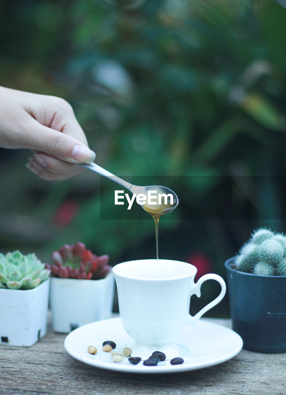 CROPPED IMAGE OF HAND POURING COFFEE CUP