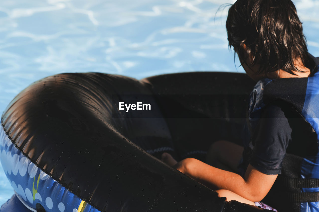 High angle view of boy in inflatable ring on swimming pool at water park