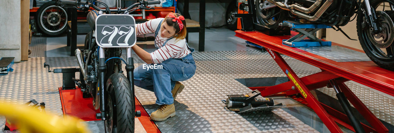Mechanic woman checking custom motorcycle on factory