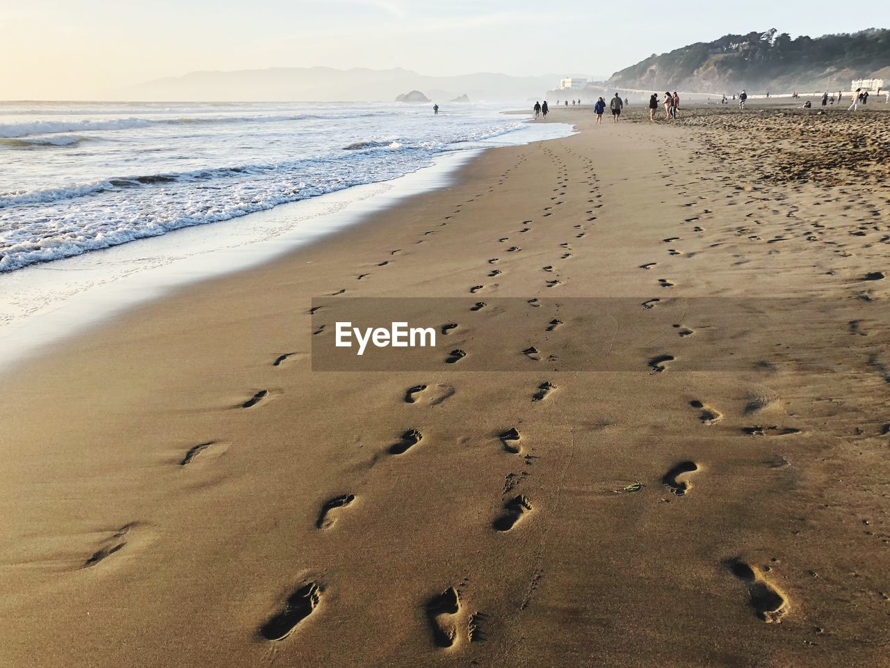 Footprints on sand at beach against sky