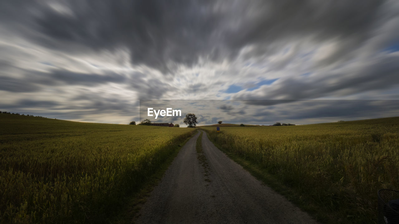 Road amidst field against sky