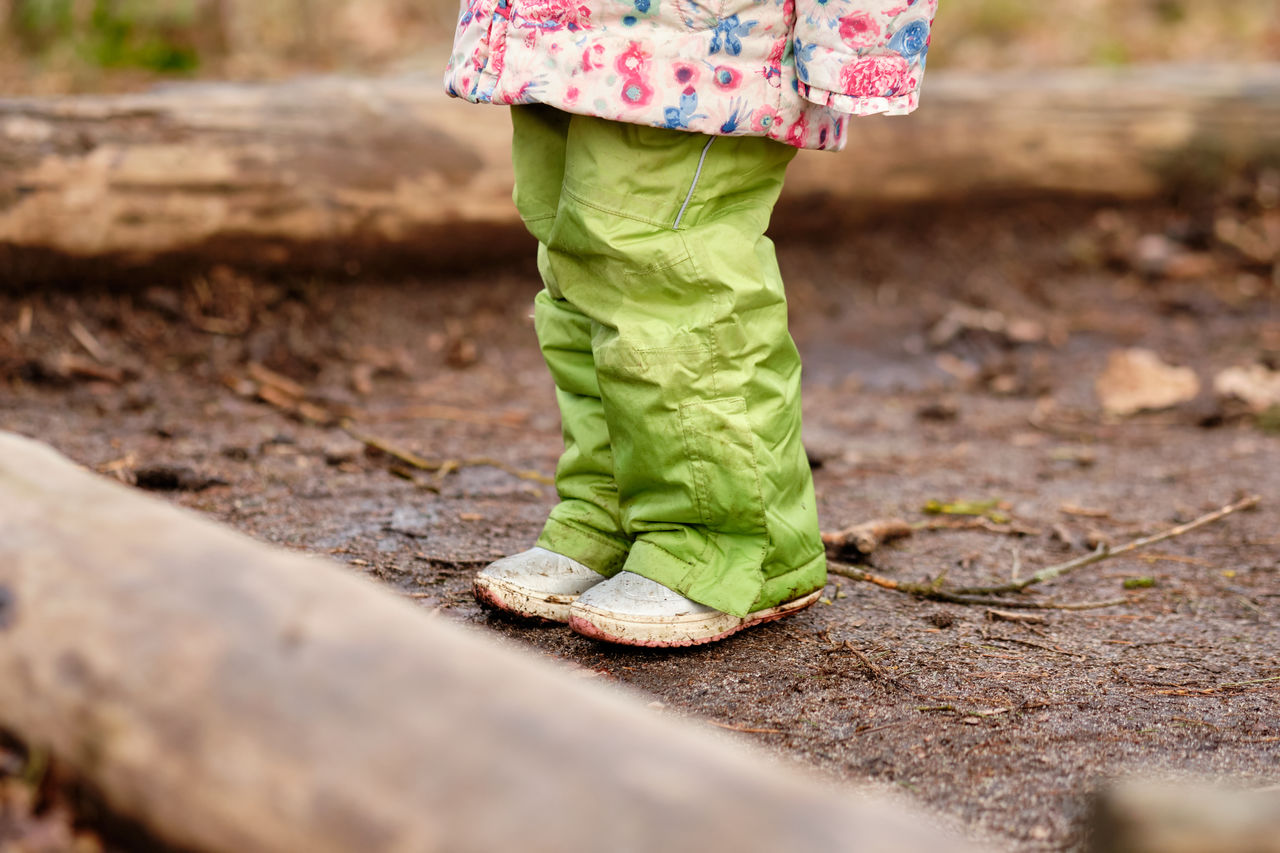 Low section of girl standing on wet field