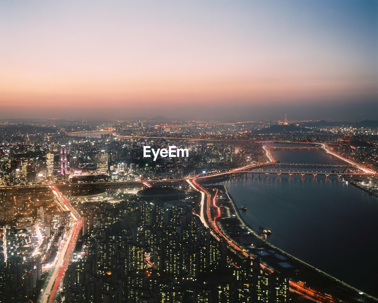 High angle view of illuminated bridge and buildings against sky at night