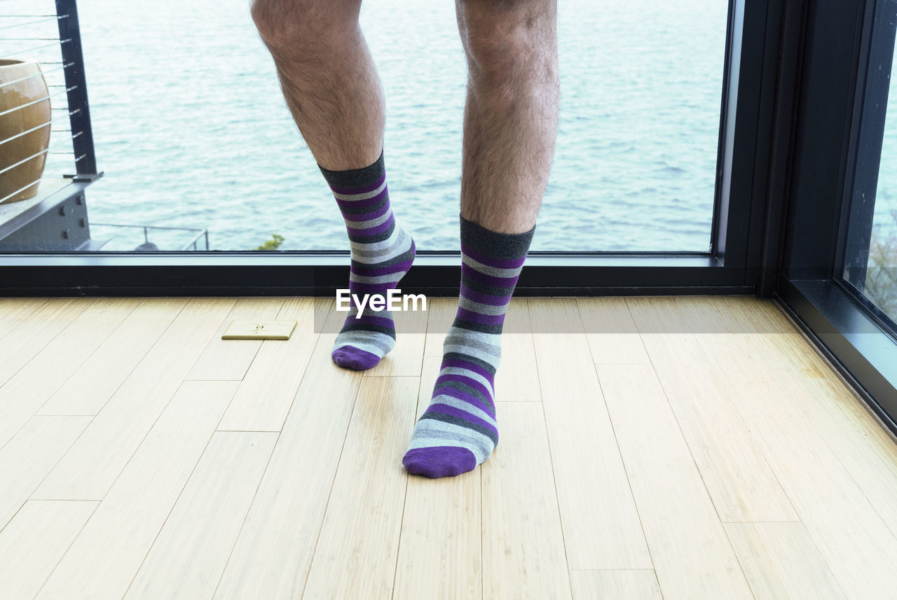 Low section of man wearing socks standing on hardwood floor