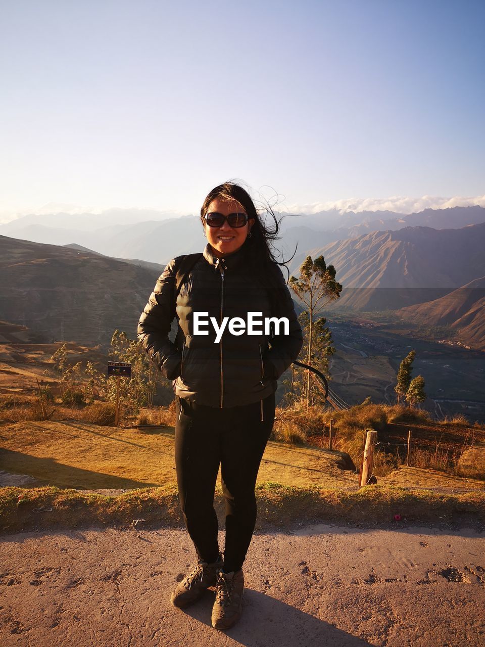 Portrait of woman wearing sunglasses standing on mountain against sky