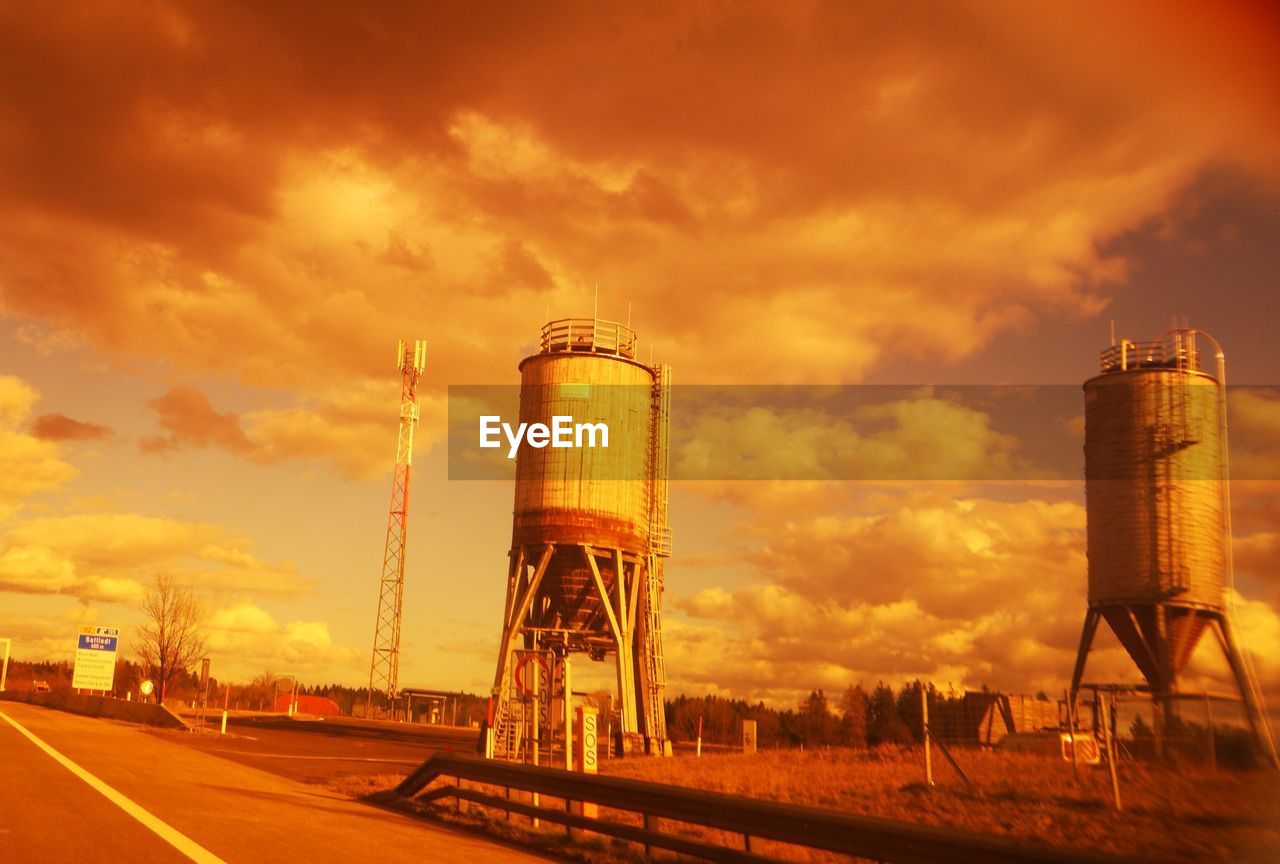 LOW ANGLE VIEW OF WATER TOWER AGAINST ORANGE SKY