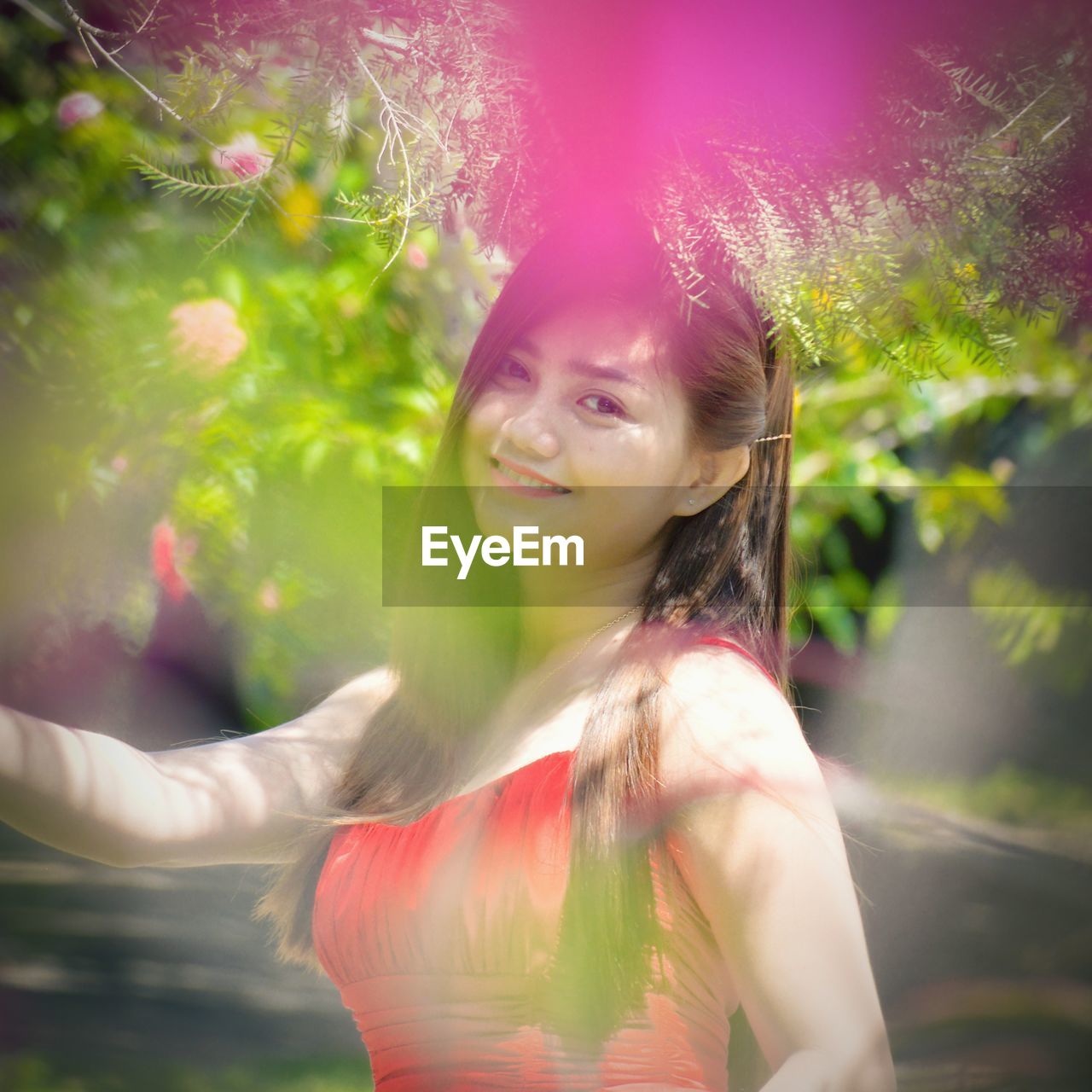 Portrait of smiling young woman standing against plants