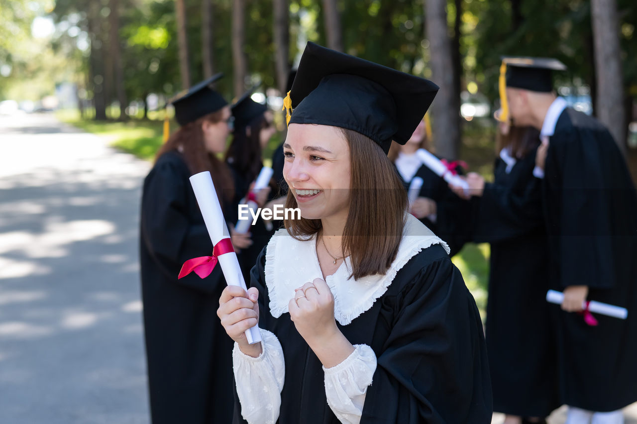 rear view of woman wearing graduation gown standing in park