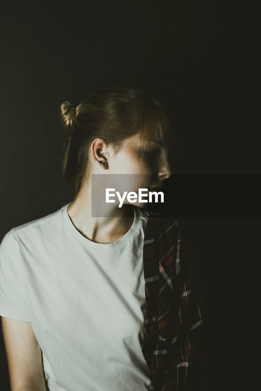 Young woman standing against black background