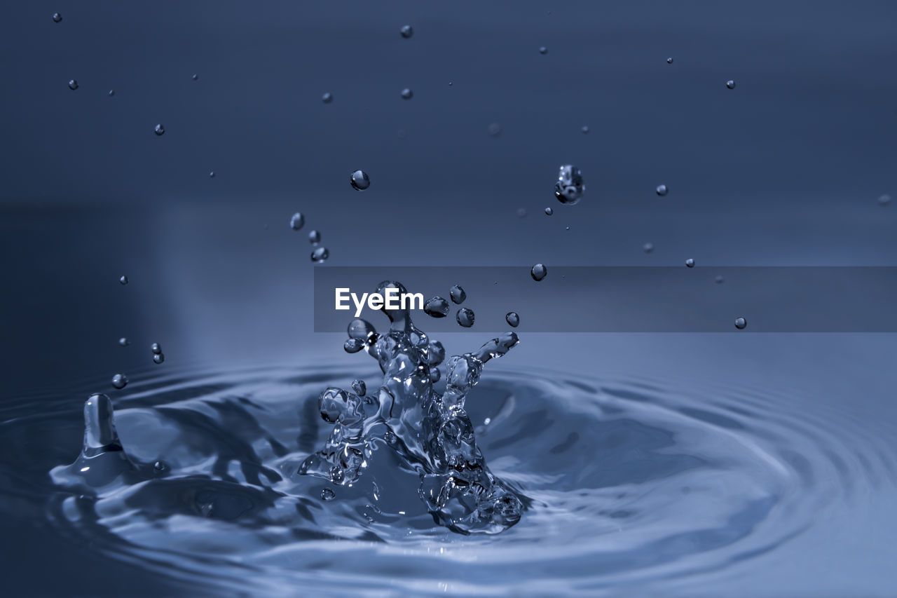 Close-up of splashing water drops causing wavy water surface