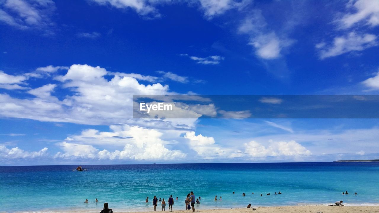 People on beach against blue sky