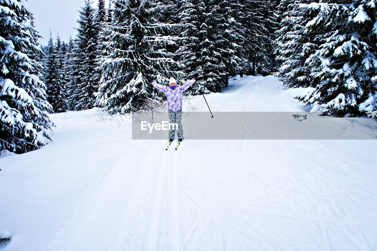 Young happy woman in winter ski clothing skiing in a beautiful coniferous fir forest. winter sport