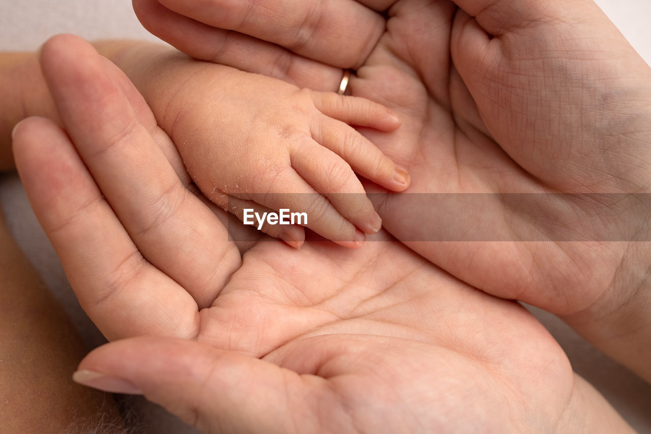 CLOSE-UP OF BABY HOLDING HANDS WITH HAND