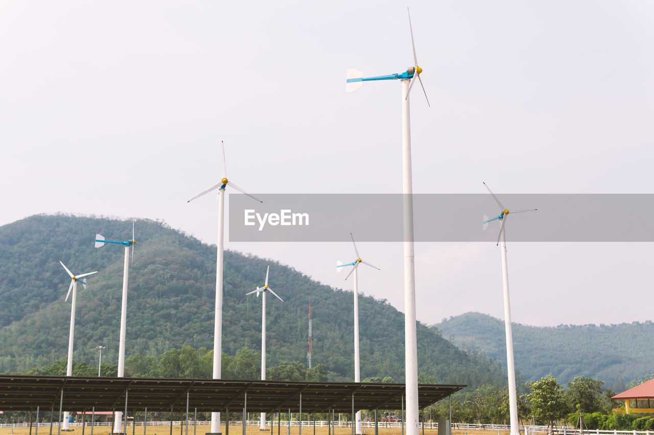 WINDMILLS ON LANDSCAPE AGAINST SKY