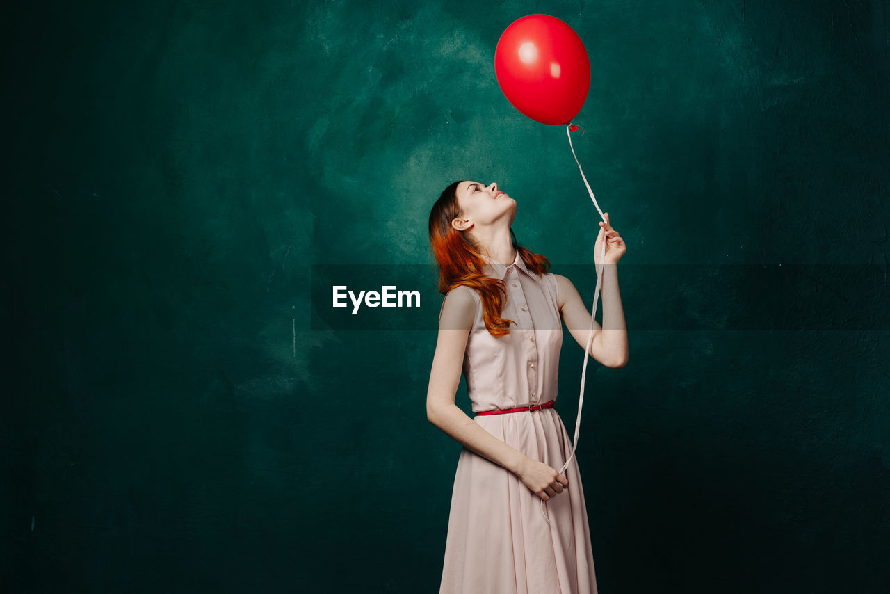 Low section of woman with balloons against blue background