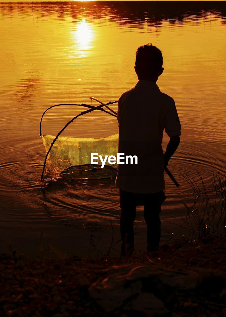 Rear view of a man fishing on lake