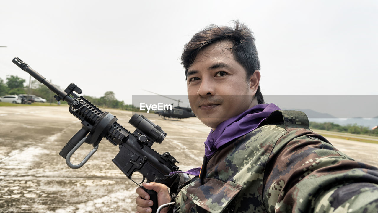 Portrait of army soldier with gun standing at air base 
