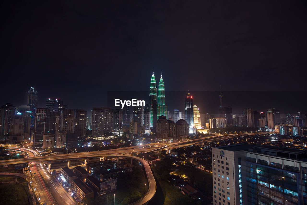 Illuminated petronas towers in city against sky at night