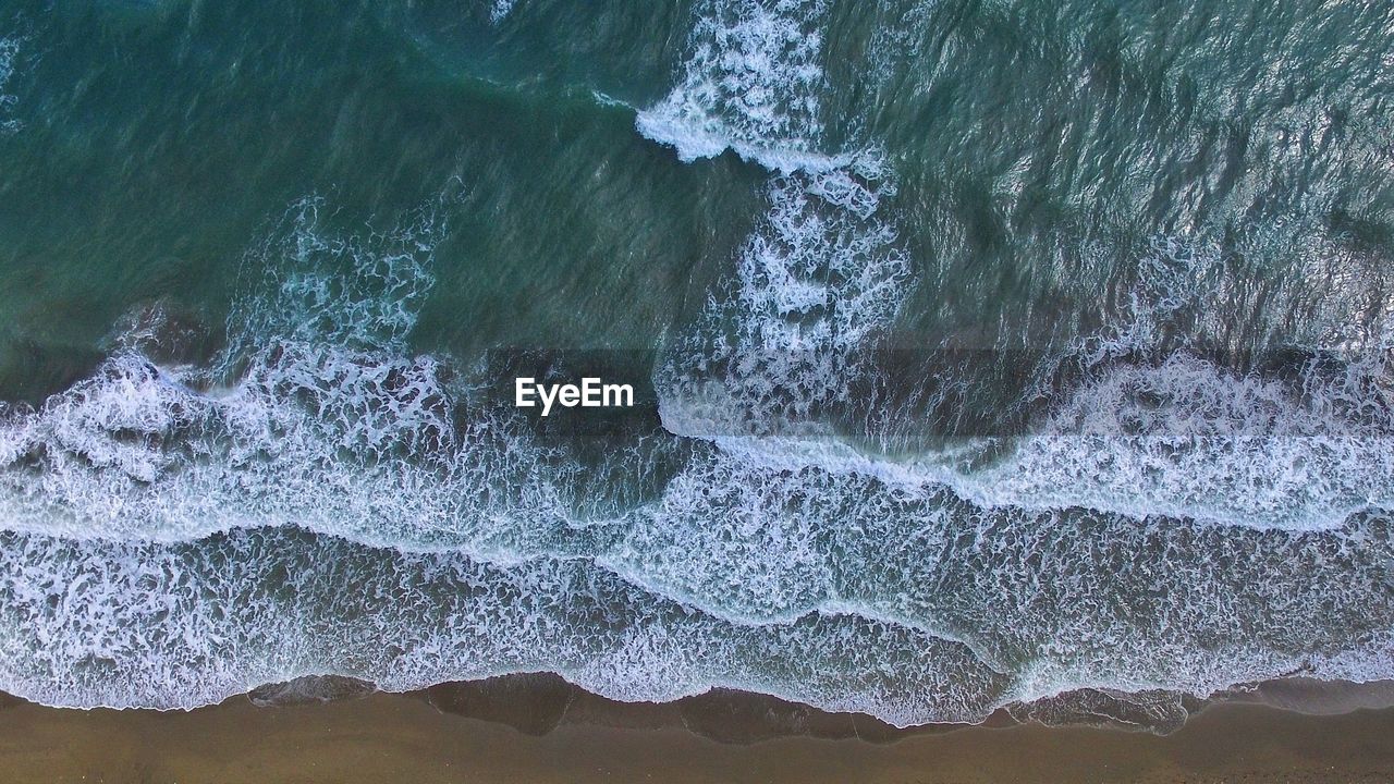 High angle view of sea waves splashing on rocks