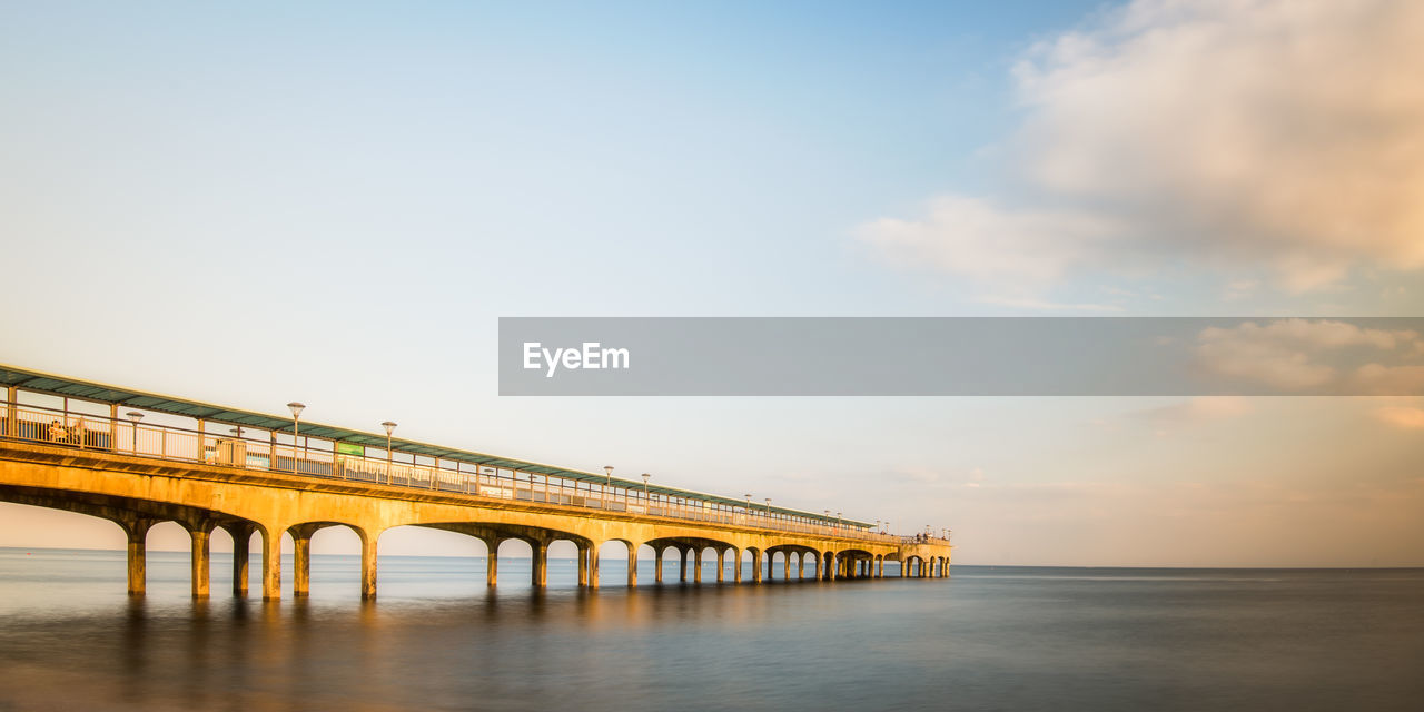 Bridge over sea against sky during sunset