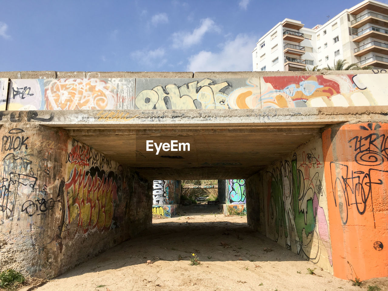 Graffiti on tunnel by building against sky