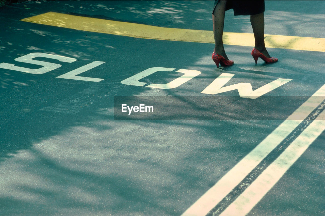 Low section of woman standing on road sign