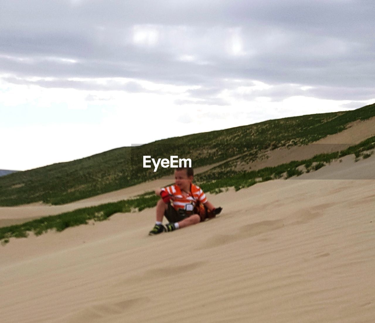 REAR VIEW OF WOMAN SITTING ON SAND