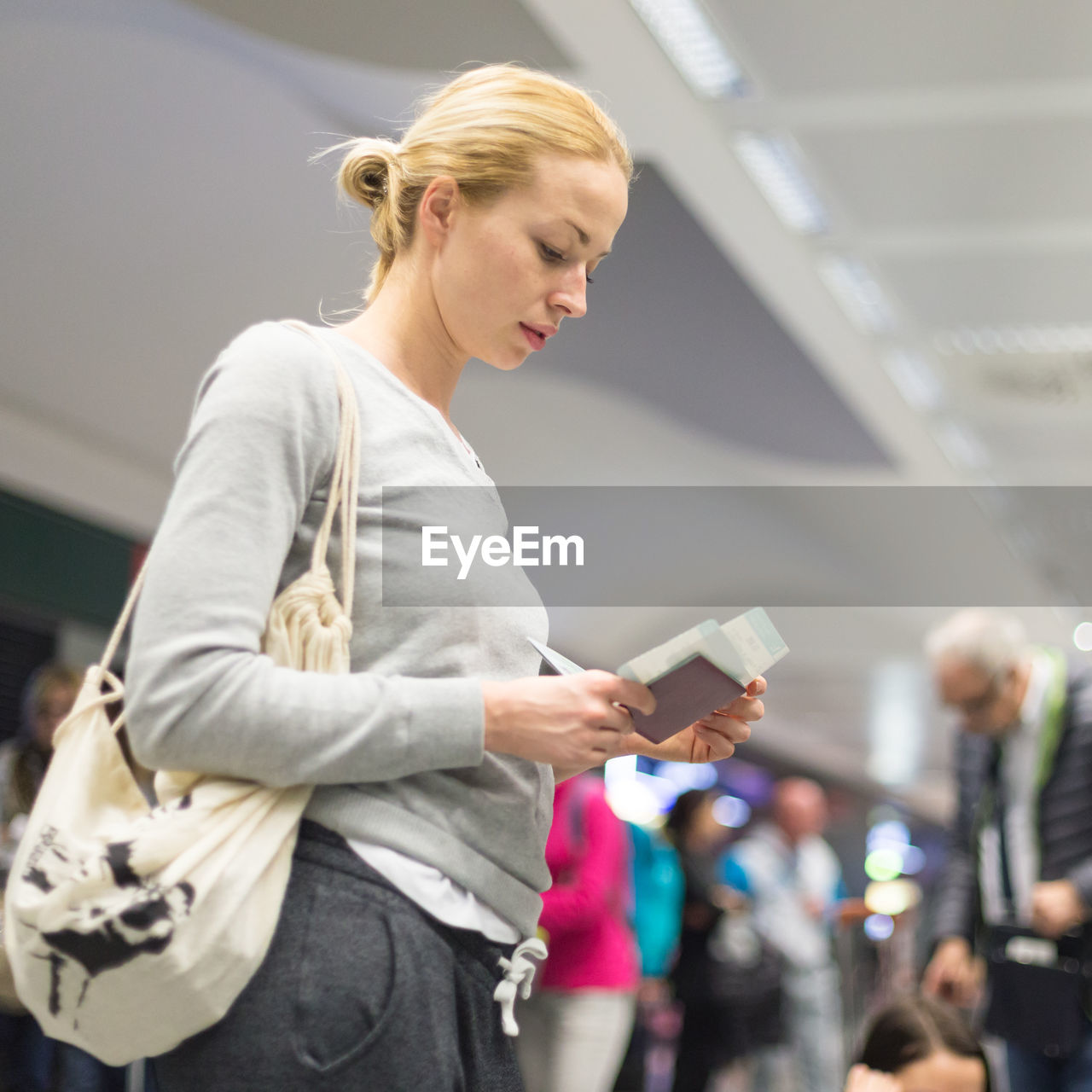 WOMAN HOLDING MOBILE PHONE WHILE STANDING ON LAPTOP IN BATHROOM