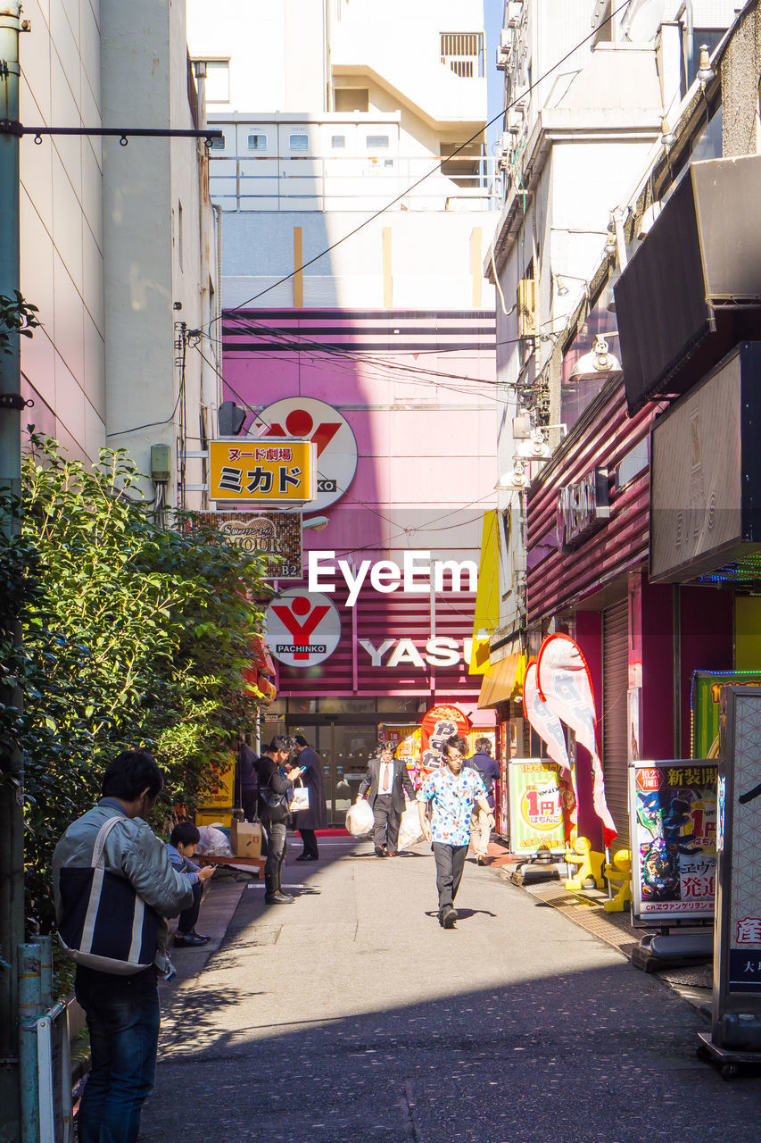 PEOPLE WALKING ON STREET AMIDST BUILDINGS