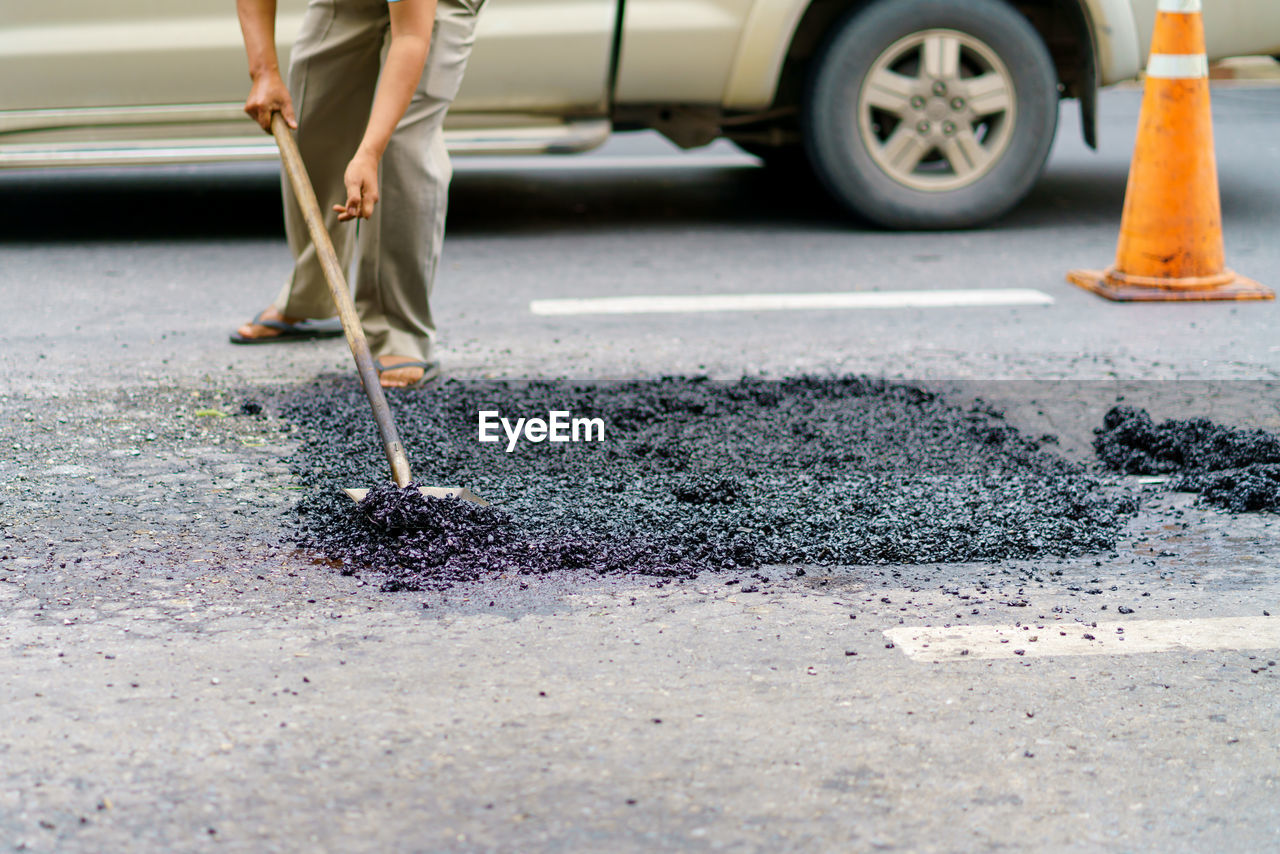 Road repair, workers and machinery are working paved road with asphalt and gravel,