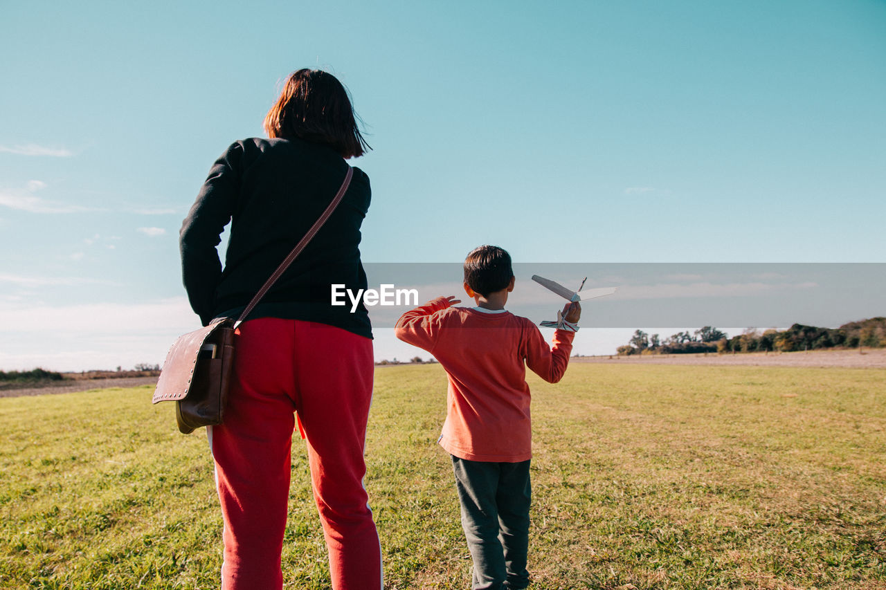 Rear view of mother and son on land against sky