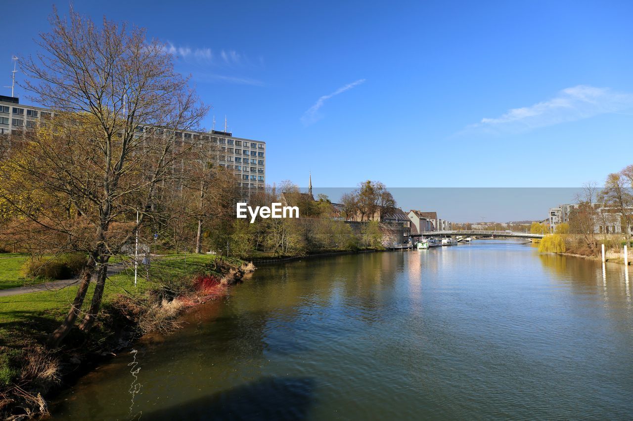 RIVER BY BUILDINGS AGAINST BLUE SKY