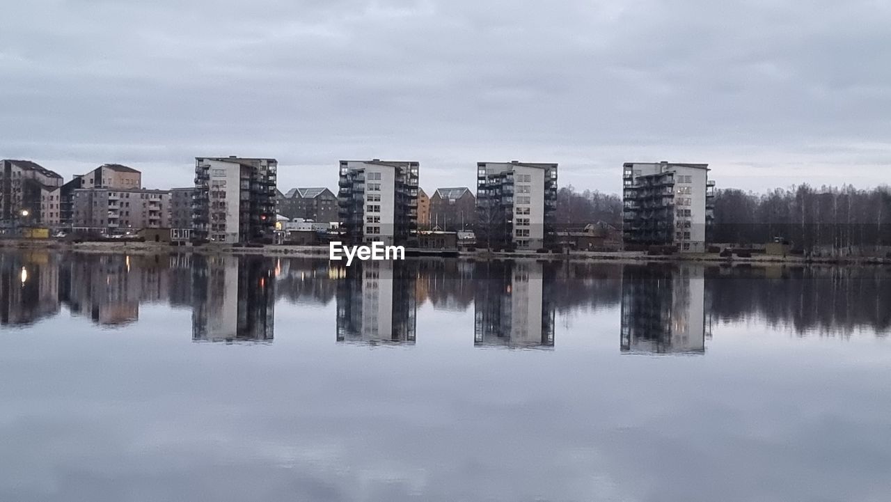 reflection, water, sky, cloud, architecture, skyline, built structure, nature, building exterior, building, no people, cityscape, lake, winter, city, waterfront, overcast, outdoors, day, tree, tranquility, landscape