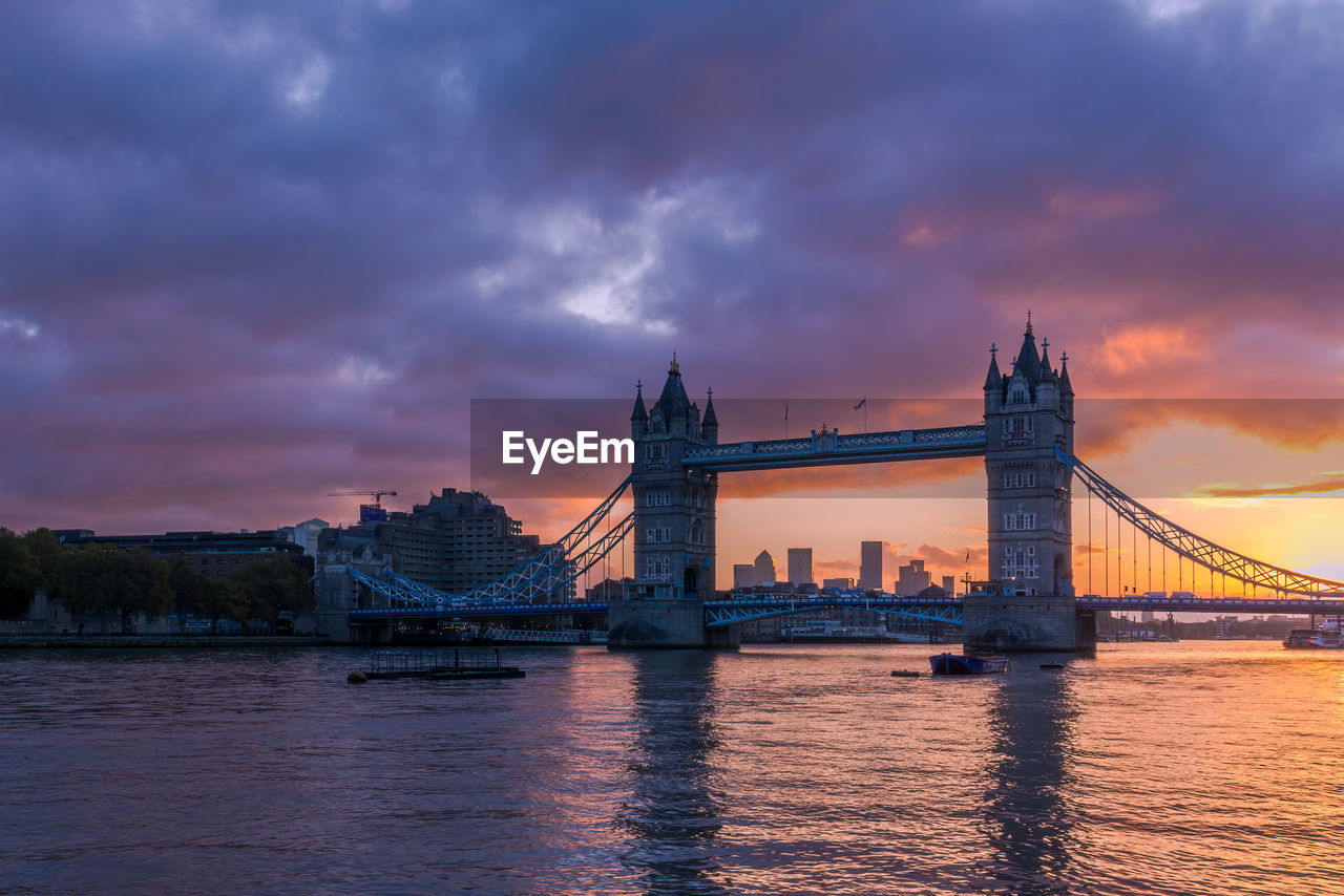 London's tower bridge illuminated by a fiery sunrise, with canary wharf in the background