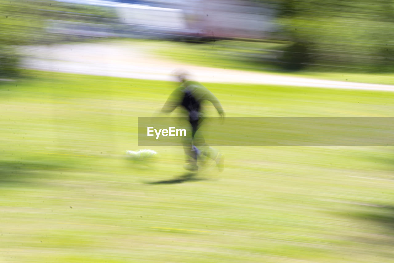 Blurred motion of boy running on grassy field